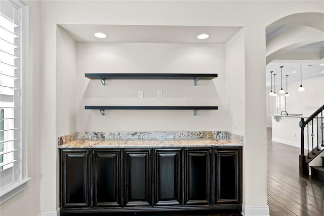 bar with hanging light fixtures, dark hardwood / wood-style floors, and light stone counters