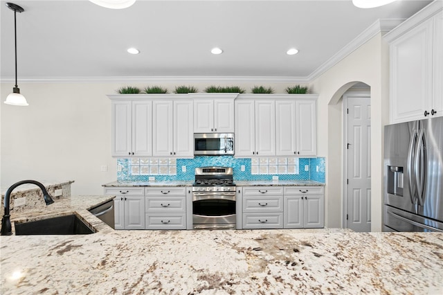 kitchen with appliances with stainless steel finishes, sink, hanging light fixtures, and white cabinets