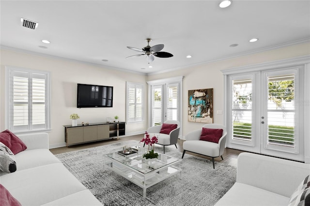 living room featuring ornamental molding, a healthy amount of sunlight, ceiling fan, and light hardwood / wood-style flooring