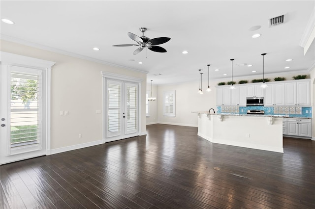 unfurnished living room featuring crown molding, ceiling fan, dark wood-type flooring, and french doors