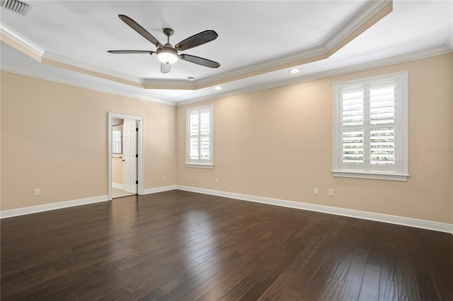 spare room with dark wood-type flooring, ceiling fan, ornamental molding, and a raised ceiling