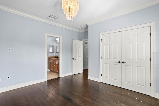 unfurnished bedroom with connected bathroom, a chandelier, dark hardwood / wood-style flooring, crown molding, and a closet