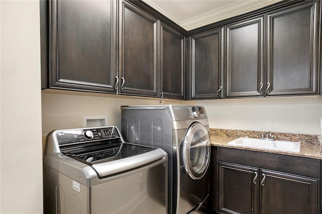 clothes washing area with cabinets, sink, and washer and clothes dryer