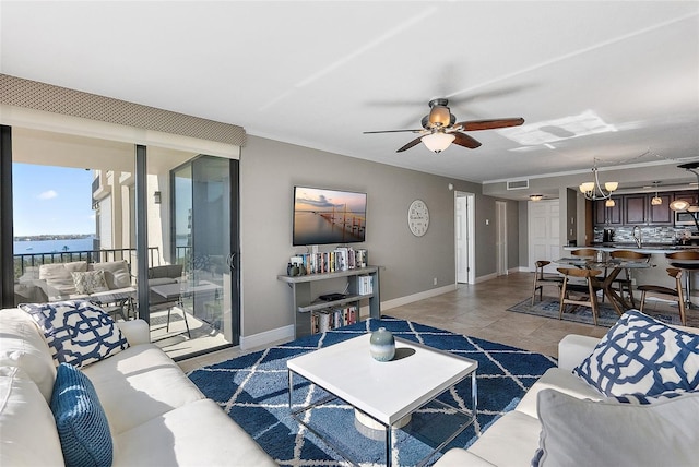 living room with ceiling fan with notable chandelier, light tile patterned flooring, and a water view