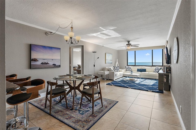 tiled dining area with a water view, ornamental molding, ceiling fan with notable chandelier, and a textured ceiling