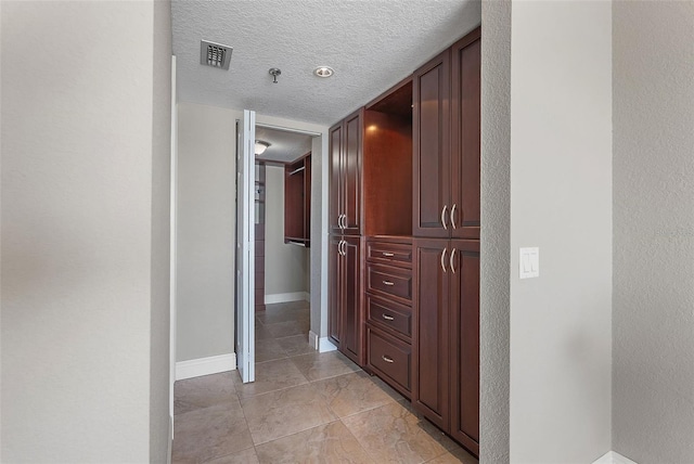 hallway featuring light tile patterned flooring and a textured ceiling