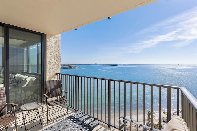 balcony with a water view and a view of the beach