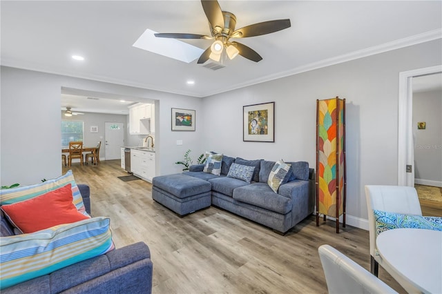 living room with sink, crown molding, light hardwood / wood-style flooring, ceiling fan, and a skylight