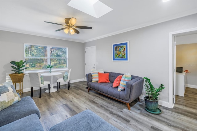 living room with light hardwood / wood-style flooring, crown molding, a skylight, and ceiling fan