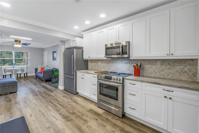 kitchen featuring crown molding, appliances with stainless steel finishes, white cabinets, and light stone counters