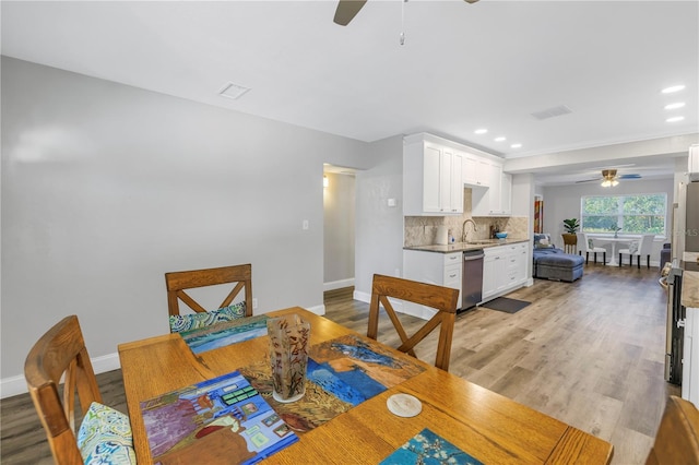 dining room with ceiling fan, sink, and light wood-type flooring