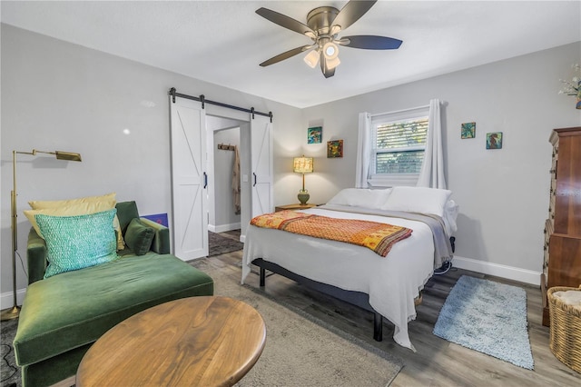 bedroom featuring hardwood / wood-style flooring, a barn door, and ceiling fan