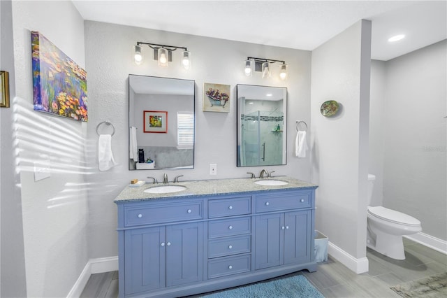 bathroom with vanity, a shower with door, and toilet