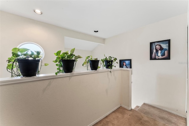 hallway with vaulted ceiling and light carpet