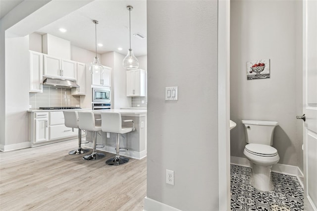 kitchen with appliances with stainless steel finishes, a kitchen breakfast bar, decorative light fixtures, and white cabinets