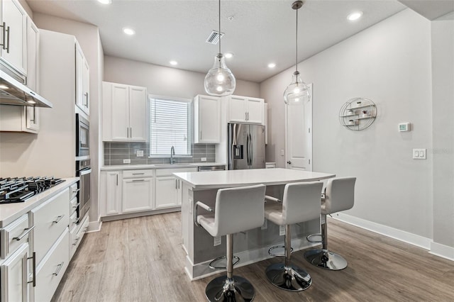 kitchen featuring sink, a breakfast bar area, white cabinetry, stainless steel appliances, and a center island