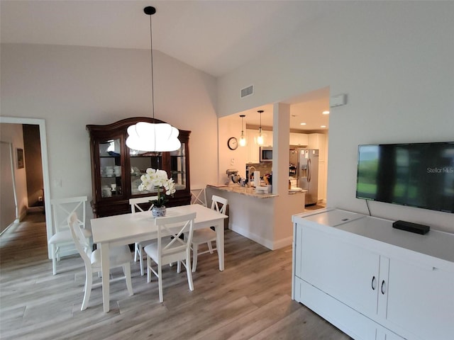 dining area with high vaulted ceiling and light wood-type flooring