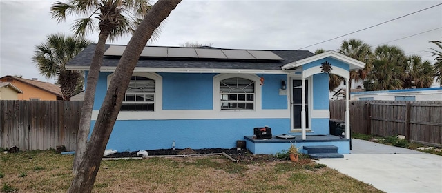 view of front of property featuring a front yard and solar panels