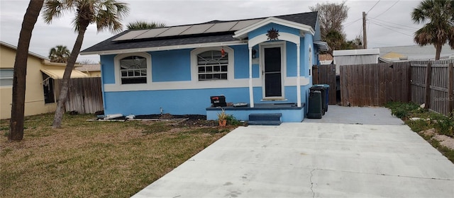 bungalow featuring a front lawn and solar panels