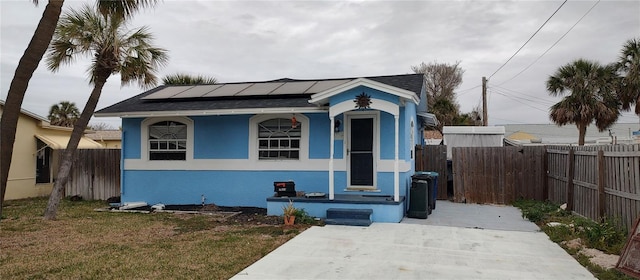 bungalow-style house featuring a front yard and solar panels