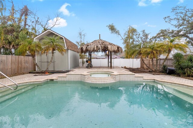 view of swimming pool featuring a fenced backyard, an outdoor structure, a fenced in pool, and an in ground hot tub