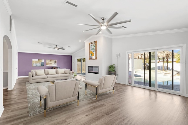 living area with arched walkways, a ceiling fan, visible vents, and crown molding