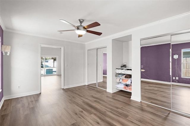 interior space with ornamental molding, wood finished floors, a ceiling fan, and baseboards