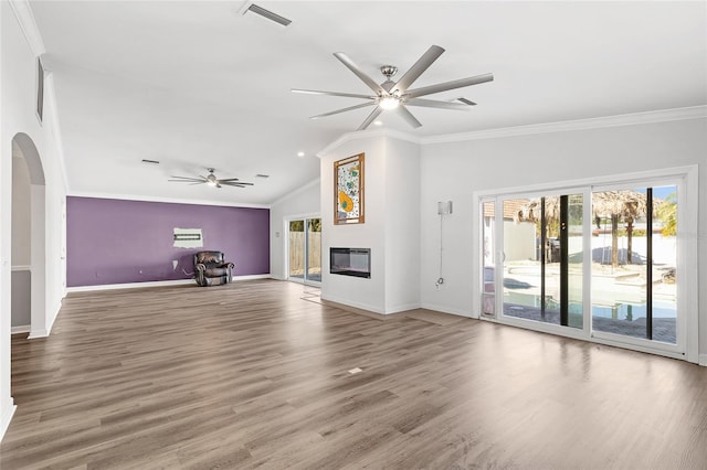 unfurnished living room featuring visible vents, arched walkways, crown molding, and a glass covered fireplace