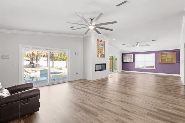 unfurnished living room featuring visible vents, ornamental molding, a glass covered fireplace, wood finished floors, and baseboards