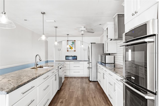 kitchen featuring ceiling fan, dark wood-type flooring, a sink, wall chimney exhaust hood, and black appliances