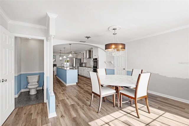 dining room featuring ornamental molding, a chandelier, light wood-style flooring, and baseboards