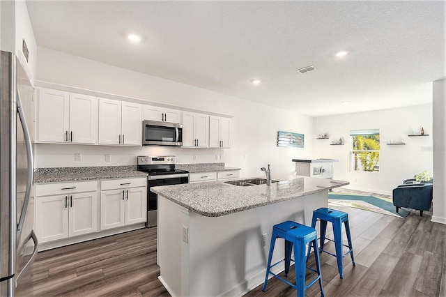 kitchen featuring appliances with stainless steel finishes, white cabinetry, sink, a breakfast bar area, and a center island with sink