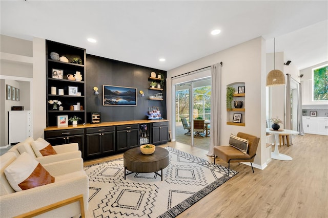 living room with bar and light wood-type flooring