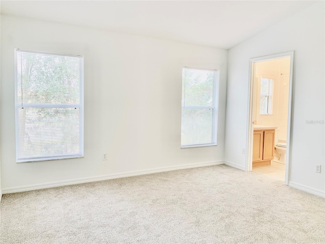 spare room with lofted ceiling and light colored carpet