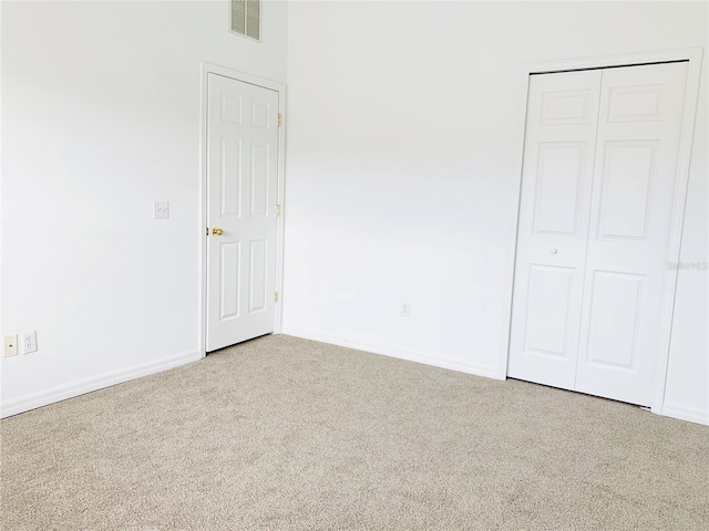 unfurnished bedroom featuring light carpet and a closet