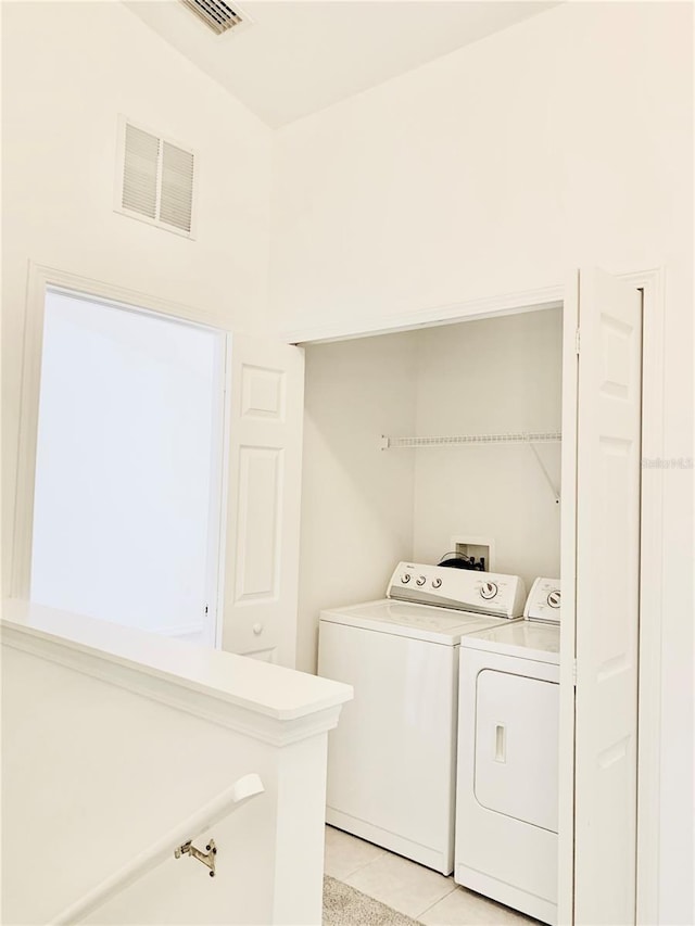 clothes washing area with light tile patterned floors and washing machine and dryer