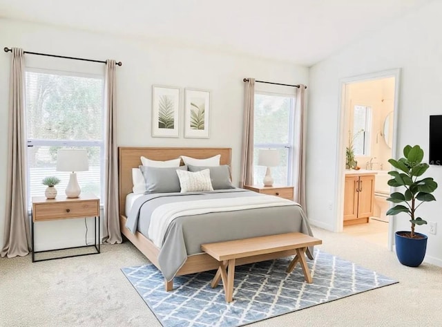 bedroom with light colored carpet, vaulted ceiling, and ensuite bath