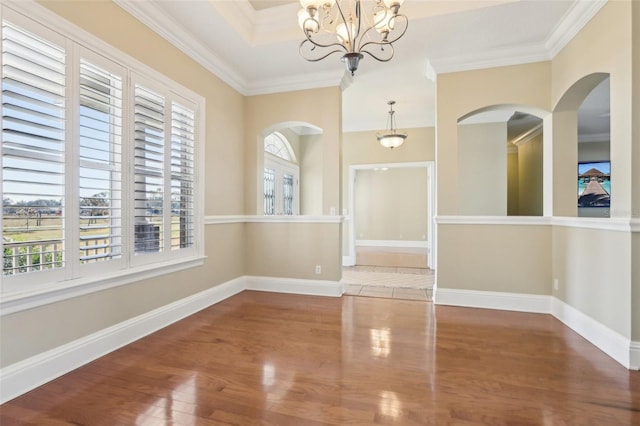 interior space featuring an inviting chandelier, ornamental molding, a raised ceiling, and hardwood / wood-style floors