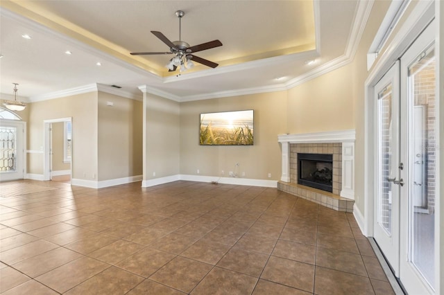 unfurnished living room featuring a tiled fireplace, a tray ceiling, tile patterned floors, and ceiling fan