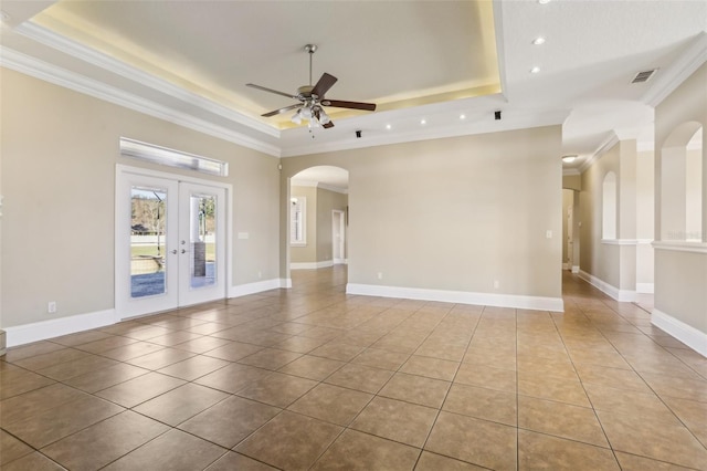 tiled empty room with crown molding, a raised ceiling, ceiling fan, and french doors