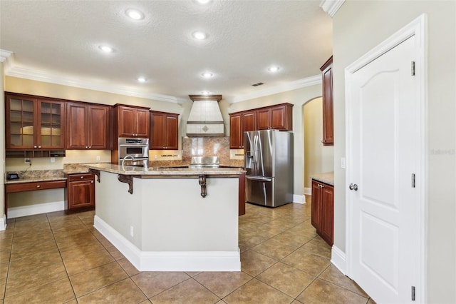 kitchen with a kitchen island with sink, a kitchen breakfast bar, custom range hood, stainless steel fridge with ice dispenser, and tile patterned floors