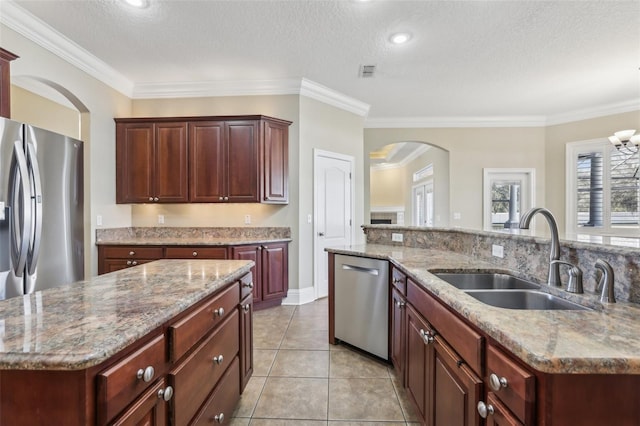 kitchen featuring a kitchen island with sink, sink, ornamental molding, and stainless steel appliances