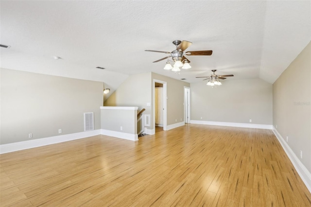 unfurnished living room featuring vaulted ceiling, a textured ceiling, and light wood-type flooring