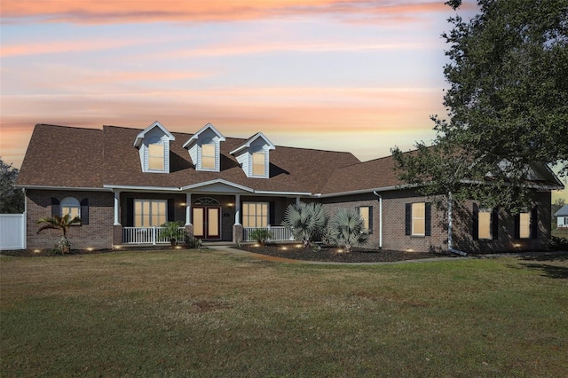 cape cod house with a lawn and covered porch