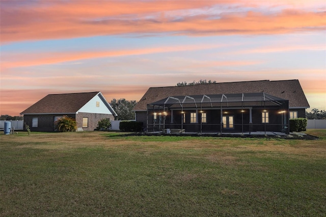 back house at dusk featuring a yard and a lanai