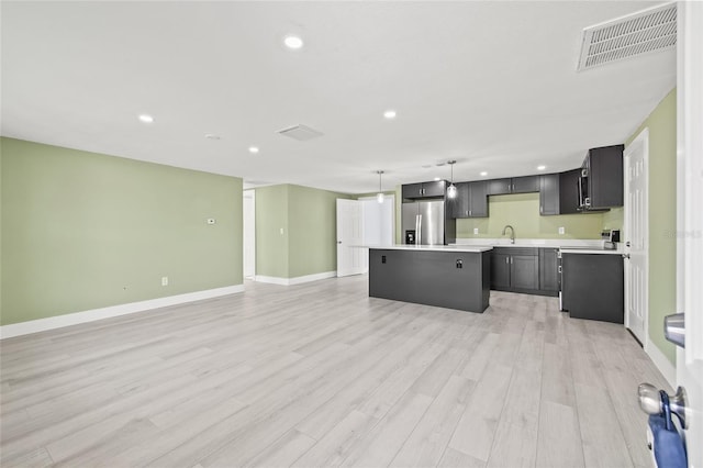 kitchen with a kitchen island, sink, hanging light fixtures, stainless steel refrigerator with ice dispenser, and light hardwood / wood-style flooring