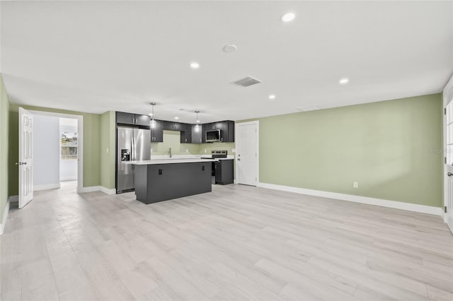 kitchen with sink, decorative light fixtures, a center island, appliances with stainless steel finishes, and light hardwood / wood-style floors