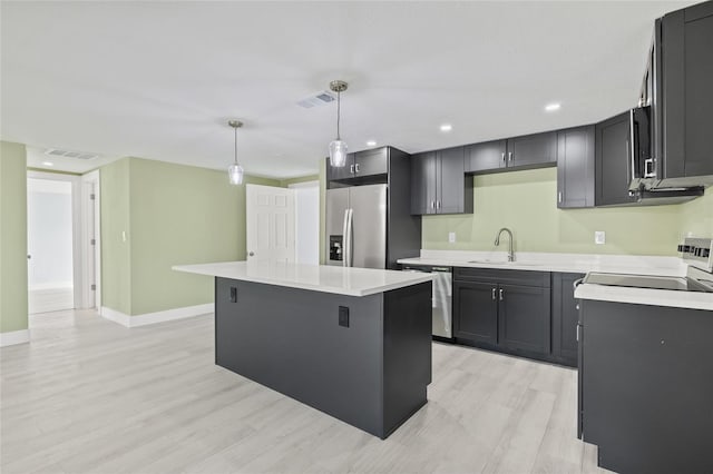 kitchen featuring sink, decorative light fixtures, a center island, light hardwood / wood-style flooring, and appliances with stainless steel finishes