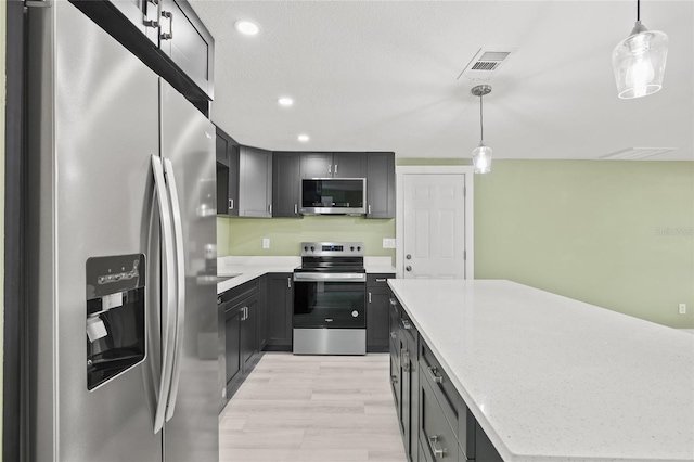 kitchen featuring hanging light fixtures, stainless steel appliances, a center island, light stone countertops, and light wood-type flooring