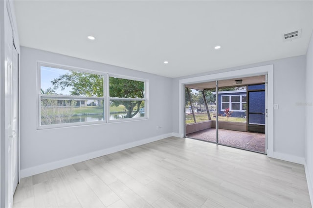 unfurnished room with light hardwood / wood-style flooring and a water view